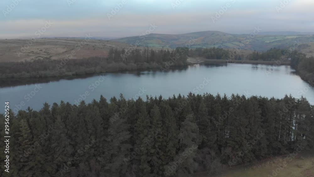 Aerial drone shot of lake surrounded by evergreen trees in winter Aerial drone shot of lake surrounded by evergreen trees in winter