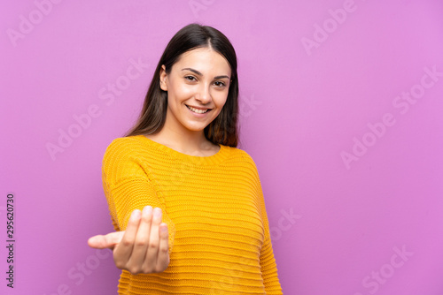 Young woman over isolated purple background inviting to come