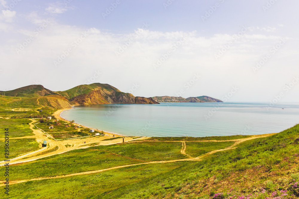 Sunny weather over a field with hills near the sea