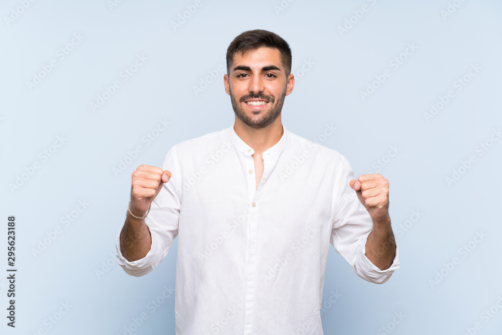 Naklejka premium Handsome man with beard over isolated blue background celebrating a victory in winner position