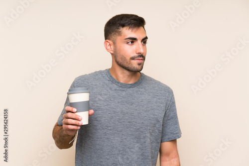 Handsome man with beard holding a take away coffee over isolated background