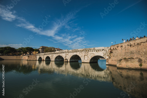 Rimini  Italy - September 11  2019  Tiberius bridge in Rimini on a background of blue sky with white clouds