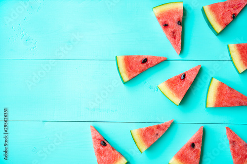 Many small pieces of watermelon are cutted and placed on real wood floors bright blue color. Show fresh, feeling at daytime of summer. Suitable for background, backdrop, advertisement with copy space.