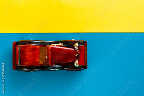 Retro vintage car on multicolored paper background. Vacation, delivery, travel concept. Top view, flat lay. .Blue yellow stipes. Vertical down direction.