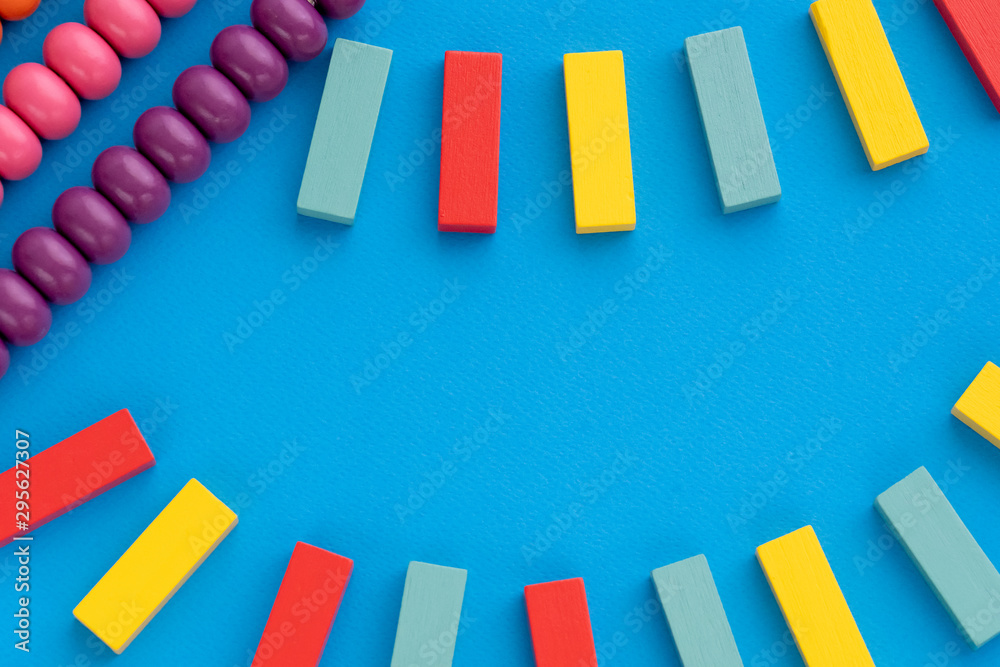 Plakat Frame from kids toys, top view on children's educational games on blue paper background. Multicolored wooden bricks, abacus. Flat lay, copy space for text