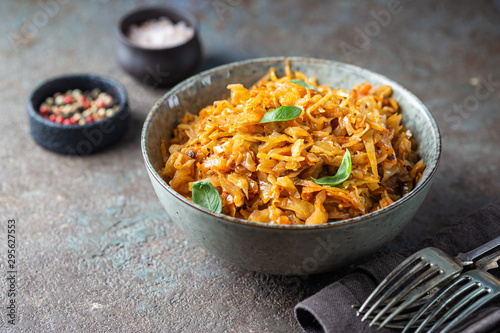 Stewed or braised cabbage served in a bowl on dark stone background, close up