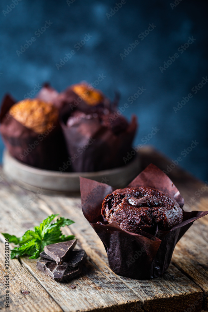 Dark chocolate muffin with mint on a wooden table, homemade baking