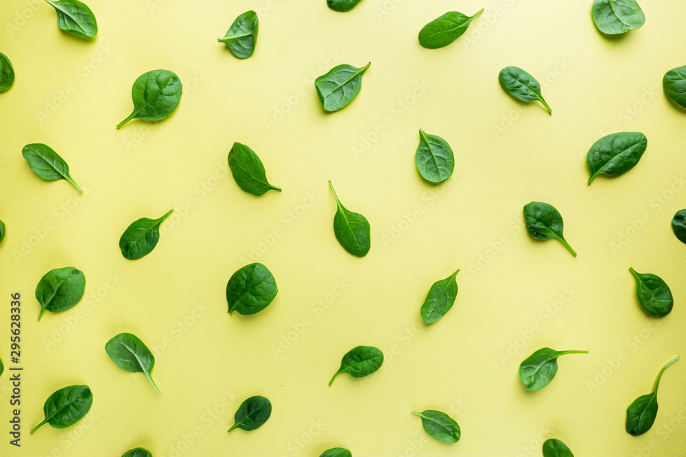 Spinach leaves pattern background on yellow, top view Spinach leaves pattern background on yellow, top view