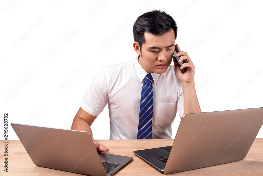 Serious Asian businessman talking on cellphone with 2 laptop Serious Asian businessman talking on cellphone with 2 laptop