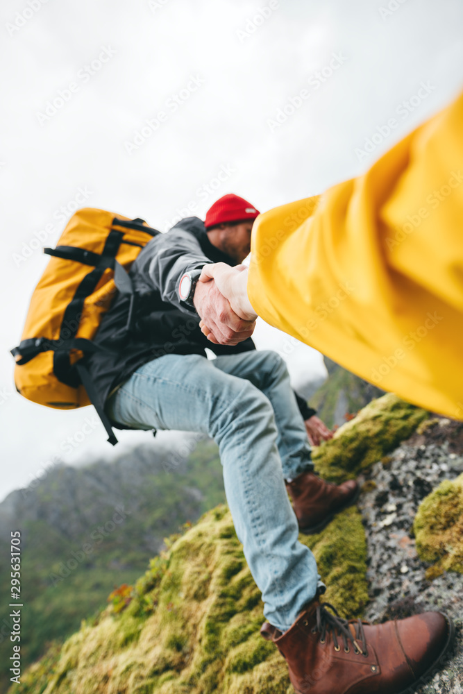 Group of two active tourist with backpack climb to rock helping each other. Brave traveler hold hand his friend for helping climb to mountain lifestyle outdoor journey. Vertical