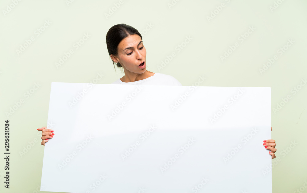 Young woman over isolated green background holding an empty white placard for insert a concept Young woman over isolated green background holding an empty white placard for insert a concept