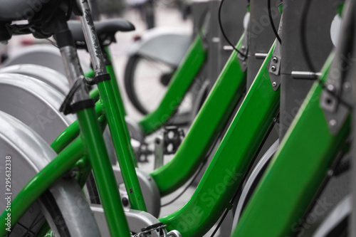 Street transportation green hybrid rent bicycles with electronic form of payment for traveling around the city stand in row on rental network parking lot waiting for cyclists to make bike trip.