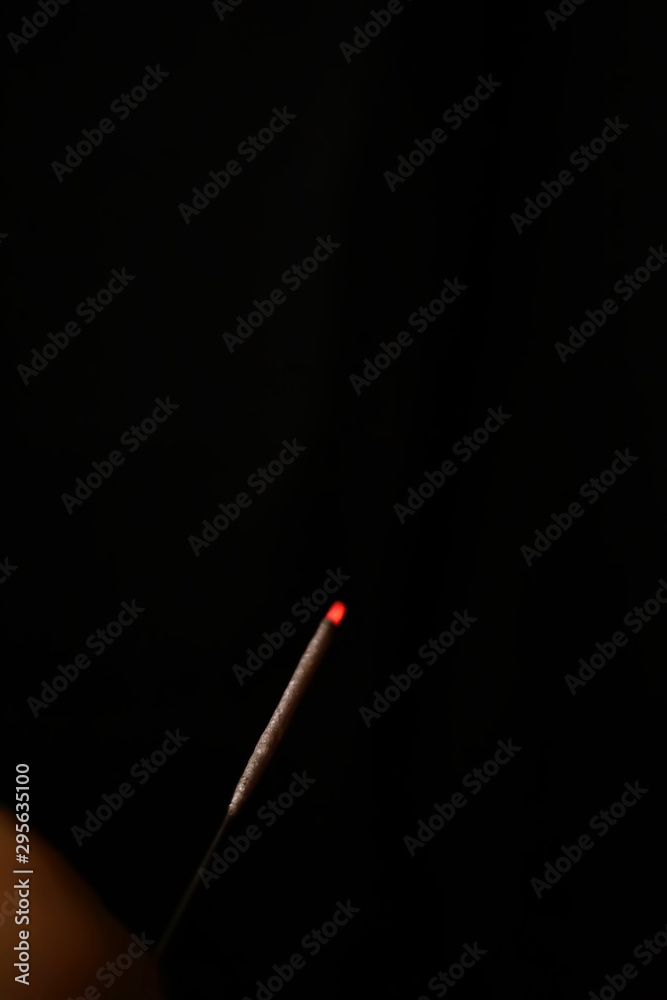 Burning sparkler firework against a black background