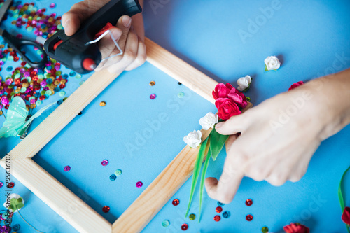 the master of decor decorates the photo frame with various colors and beauty objects, the decorator prepares equipment for the event top claas, the craftsman’s hands