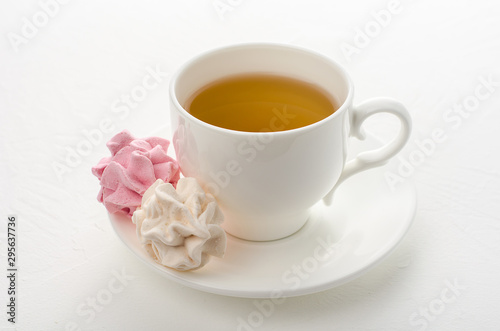 Cup of tea with marshmallows on a white background.