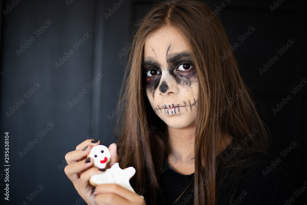A girl with scary makeup breaks a gingerbread cookie man Stock Photo |  Adobe Stock