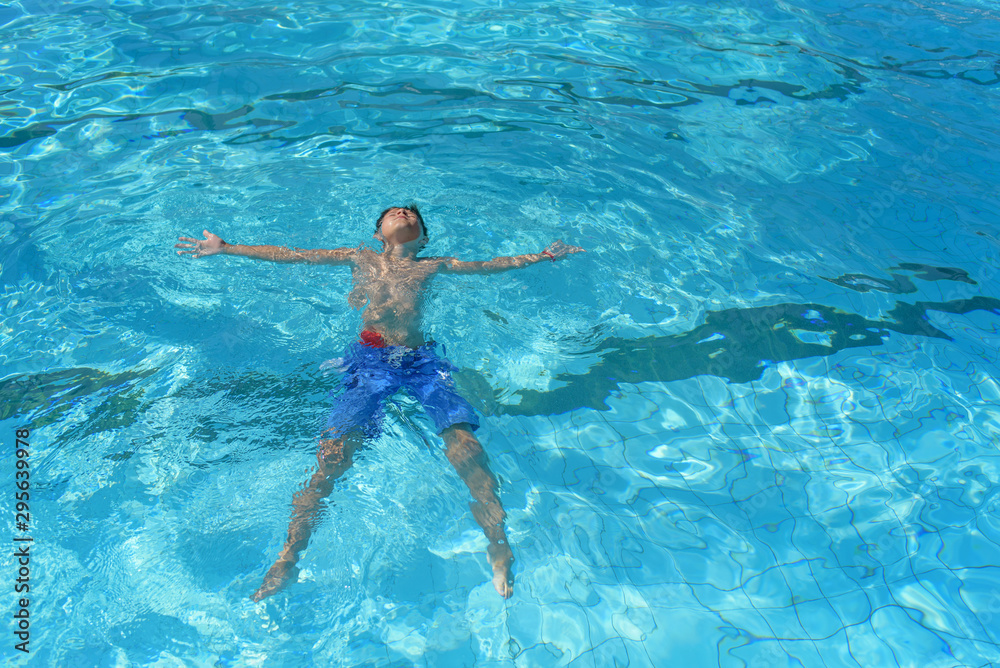 Healthy lifestyle. European boy in blue swim shorts swimming in the blue clear sea water during his trip to Spain.