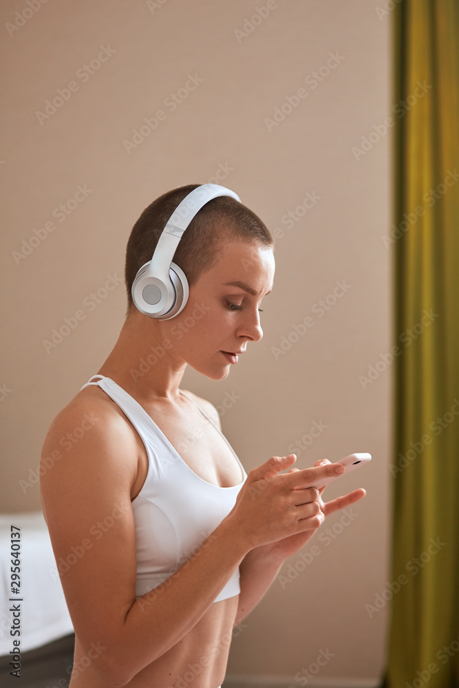 Caucasian american female exercise for lose weight, increase flexibility. Short-haired woman in headphones preparing to exercise Caucasian american female exercise for lose weight, increase flexibility. Short-haired woman in headphones preparing to exercise