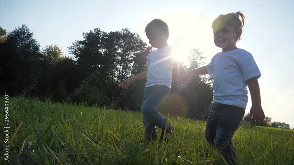 Happy children holding hands are on the green grass. Enjoy the fresh air in the countryside. Summer outing for the children. Healthy lifestyle. Happy children holding hands are on the green grass. Enjoy the fresh air in the countryside. Summer outing for the children. Healthy lifestyle.