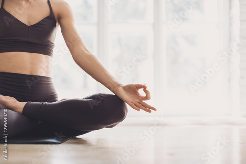 Young woman practicing yoga at class. Beautiful girl doing meditating exercises at home. Harmony, balance, meditation, relaxation, healthy lifestyle concept