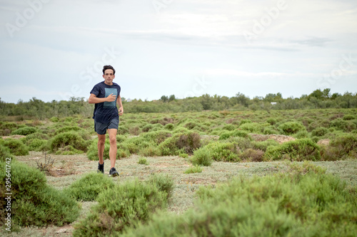 runner running in a field full of bushes, the boy is dressed in blue