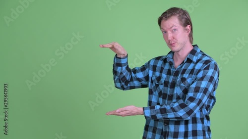 Happy young handsome hipster man snapping fingers and showing something