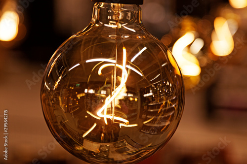 light bulb in with filament in close-up and bokeh background © Peter
