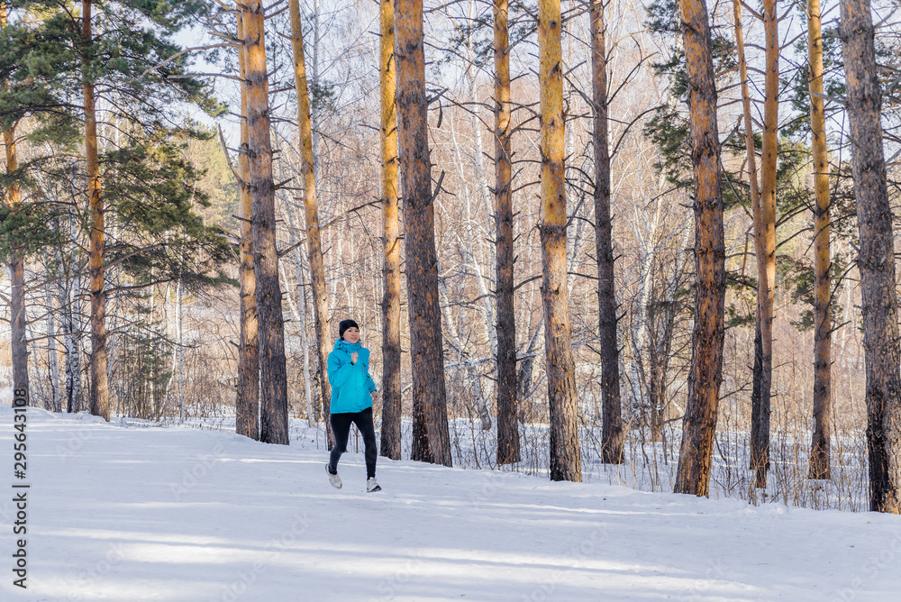 Winter cross-country exercise. Runner runs in the snow. Young female fitness model doing sports in the cold season, hardening. the concept of health Winter cross-country exercise. Runner runs in the snow. Young female fitness model doing sports in the cold season, hardening. the concept of health