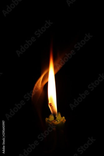 One light candle burning brightly in the black background.