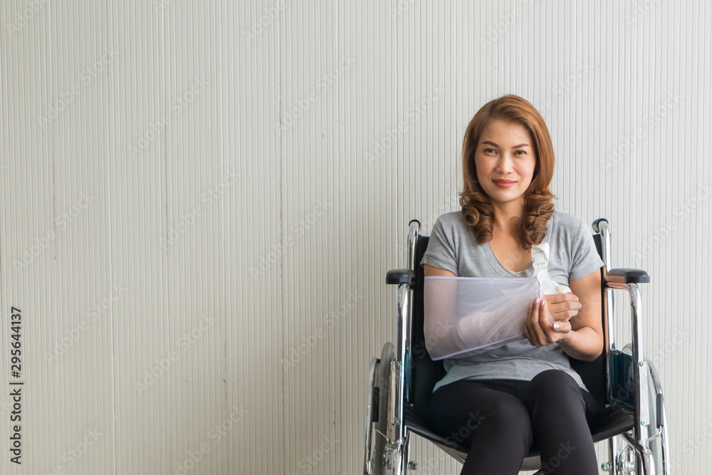 Broken arm Asian woman with arm sling sponsored in her hands sitting on a wheelchair Ideas for accident Injuries and health care Studio shot on a white background.