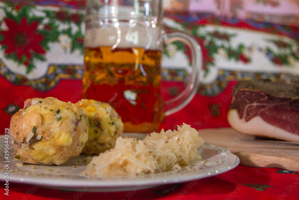 two knodels on the plate with sauerkraut and speck on the background and mug of beer and Christmas tablecloth two knodels on the plate with sauerkraut and speck on the background and mug of beer and Christmas tablecloth