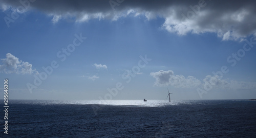 Seascape, wind turbine in the distance on the sea, blue sky and clouds