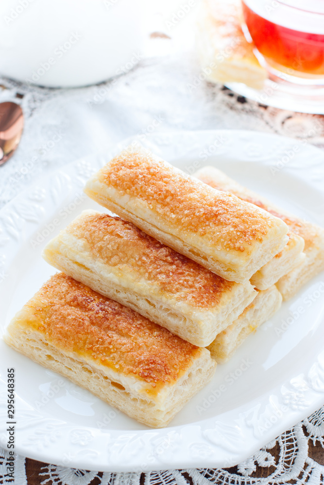 Baking tongues from puff pastry with sugar on a white plate, selective focus Baking tongues from puff pastry with sugar on a white plate, selective focus