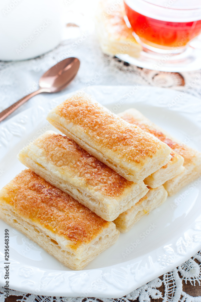 Baking tongues from puff pastry with sugar on a white plate, selective focus