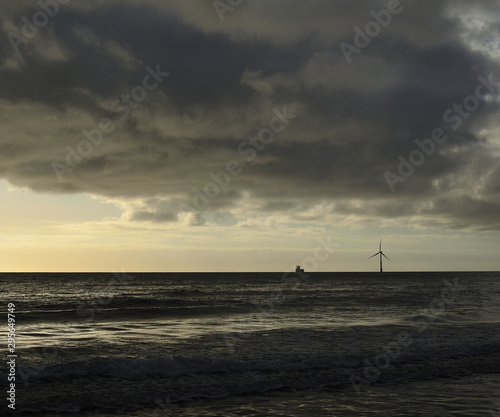 Seascape at dawn with waves, cloudy sky and wind turbine on the sea, coast of Gran Canaria