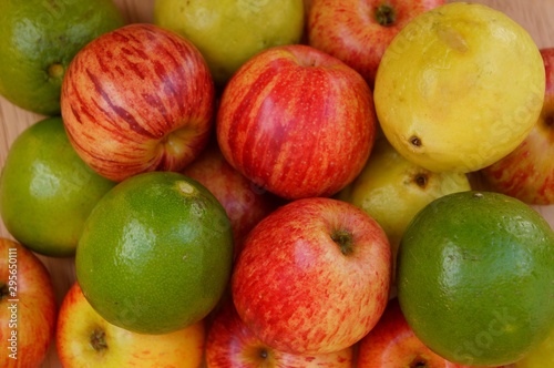 Red apples  limes and guavas on wooden background. 