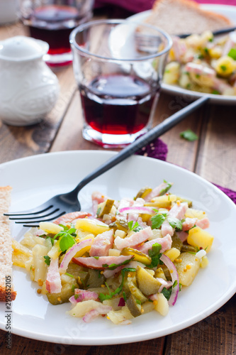 traditional german potato salad with sausage and pickled cucumbers, selective focus