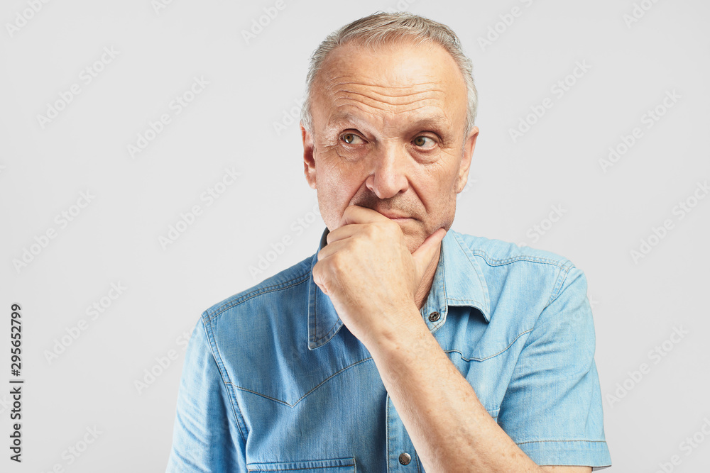 Portrait of a stylish modern elderly man on a white background in the studio. Senior boss thinking in a pensive pose Portrait of a stylish modern elderly man on a white background in the studio. Senior boss thinking in a pensive pose