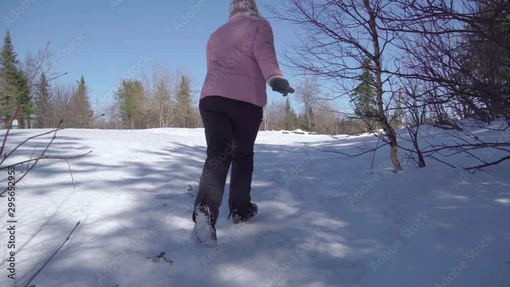 Granny runs through the winter forest and plays a children's game of hide and seek. A woman aged is very happy.