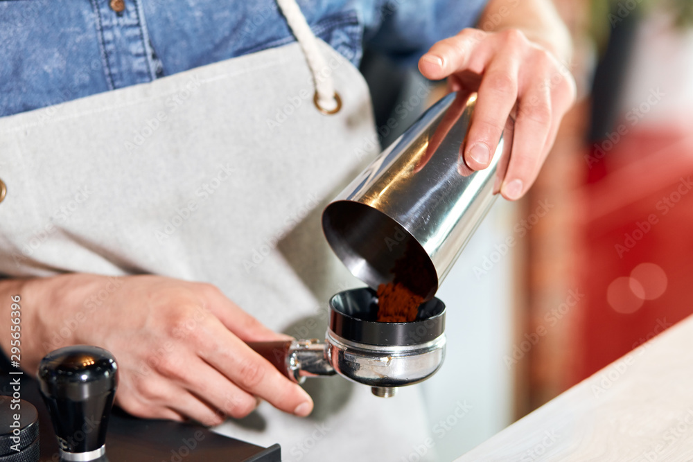Male hands puts ground coffee into tamper at bar counter, Barista takes order to make cup of hot aromatic cappuccino for friendly guests, close up Male hands puts ground coffee into tamper at bar counter, Barista takes order to make cup of hot aromatic cappuccino for friendly guests, close up