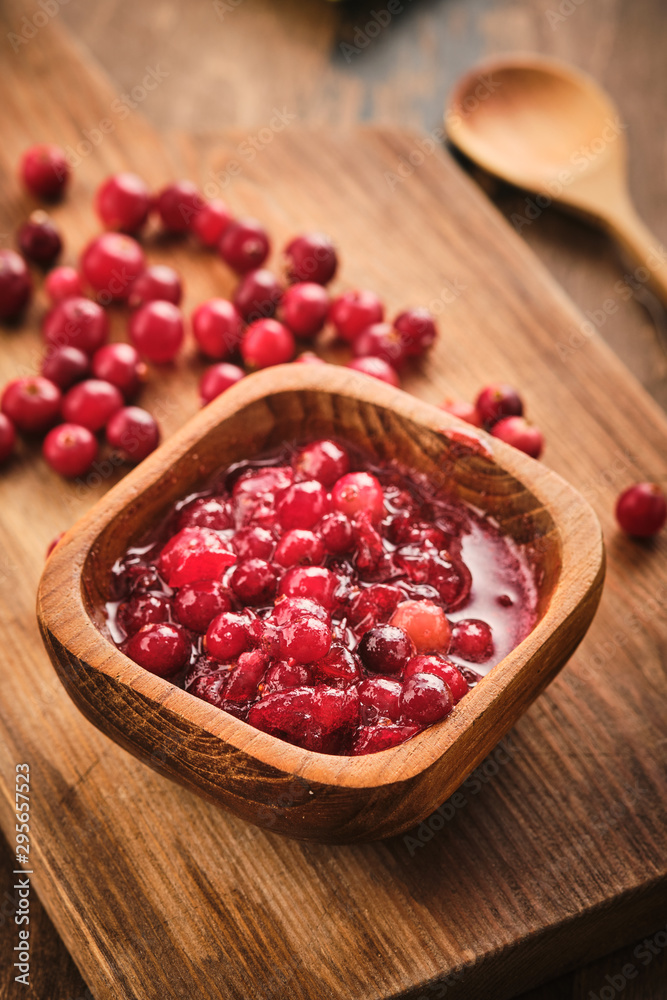 Cranberry jam in a wooden bowl on a wooden background. Cranberry jam in a wooden bowl on a wooden background.