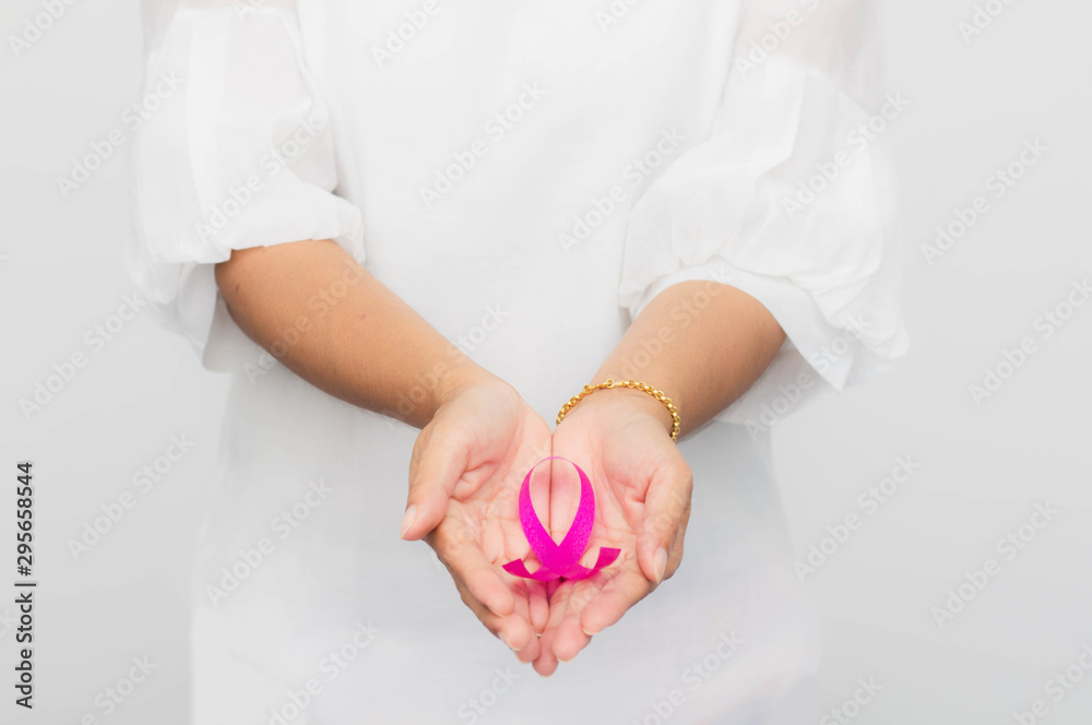 Pink ribbon on woman hand to support breast cancer cause. Healthcare, medicine and breast cancer awareness concept. Pink ribbon on woman hand to support breast cancer cause. Healthcare, medicine and breast cancer awareness concept.