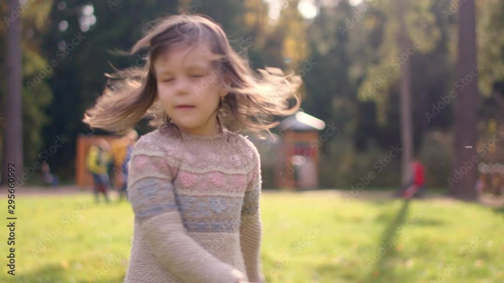 Little cheerful girl playing and fooling around on playground in the autumn city park, slow motion shot. Little cheerful girl playing and fooling around on playground in the autumn city park, slow motion shot.