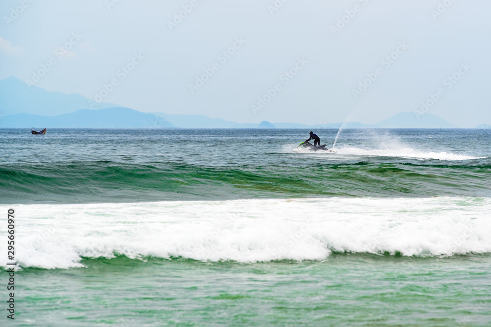 Black dressed man jumps on the jet ski above the sea waves