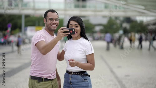 Happy young couple posing for self portrait on square. Smiling friends having fun while posing for selfie. Concept of self portrait photo