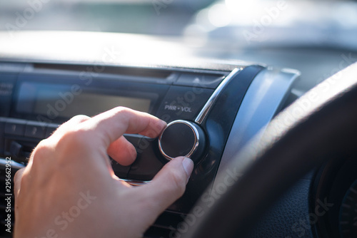 People hand is control sound volume of radio in the car while listening to music.