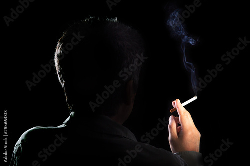 Mysterious man with cigarette and smoke isolated on a black background. Smoking kills. concept of the dangers of smoking.