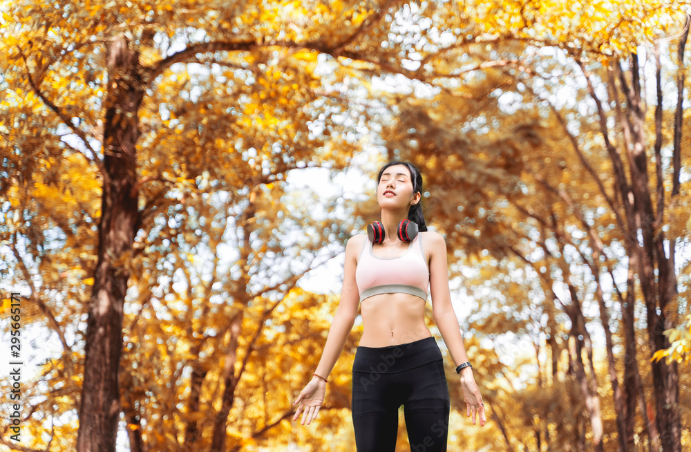 Healthy woman are inhaling fresh air during exercise in a happy and relaxing mood at the park with autumn leaves blur bokeh background and sunlight in sport and healthy concept with copy space. Healthy woman are inhaling fresh air during exercise in a happy and relaxing mood at the park with autumn leaves blur bokeh background and sunlight in sport and healthy concept with copy space.