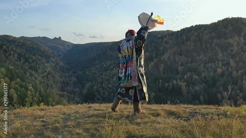 Siberian shaman performs a ritual dance and beats a tambourine on the top of the mountain.