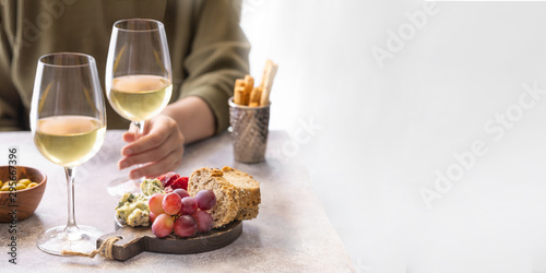 .Woman holding glass of white wine in the restaurant. Different snacks, Blue cheese, olives, baguette slices and cured meat. Tasting party lifestyle background for Banner with copy space.